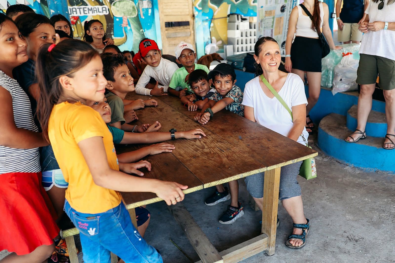 Volunteer smiling with local children at best volunteer vacation programs Guatemala inside a colorful community space. 