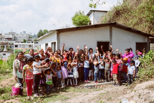 Be Humanitarian volunteers with local mothers and children outside a community building in Guatemala
