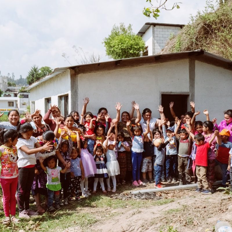Be Humanitarian volunteers with local mothers and children outside a community building in Guatemala