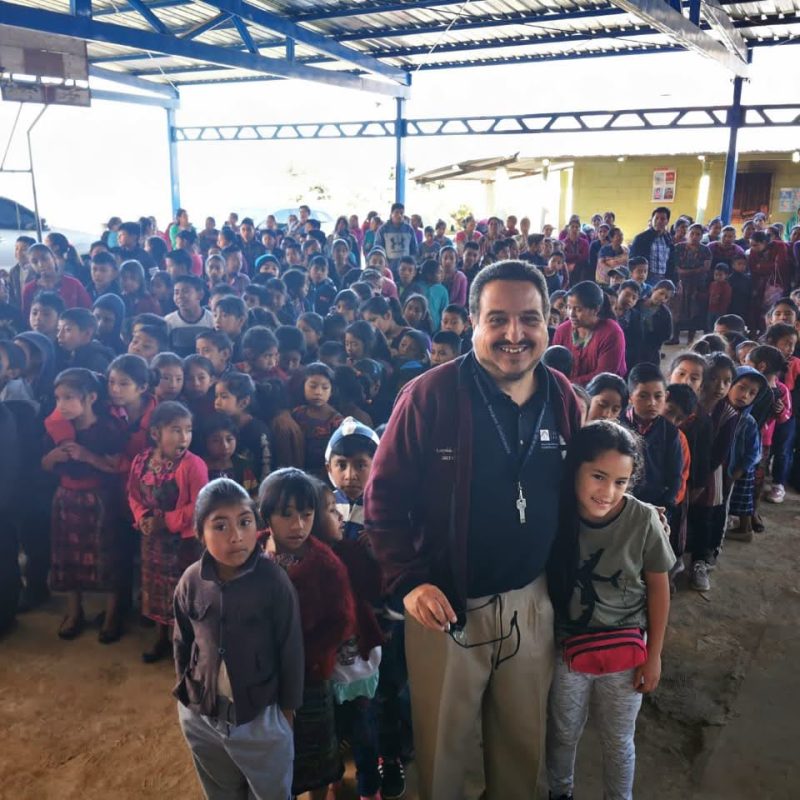 Man with students during an outreach event for the best Guatemala volunteer vacation programs for seniors.