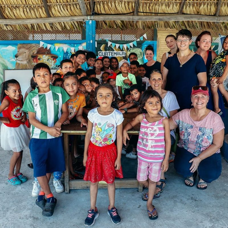 Top senior volunteer travel opportunities in Guatemala: volunteers posing with local children at a community school.