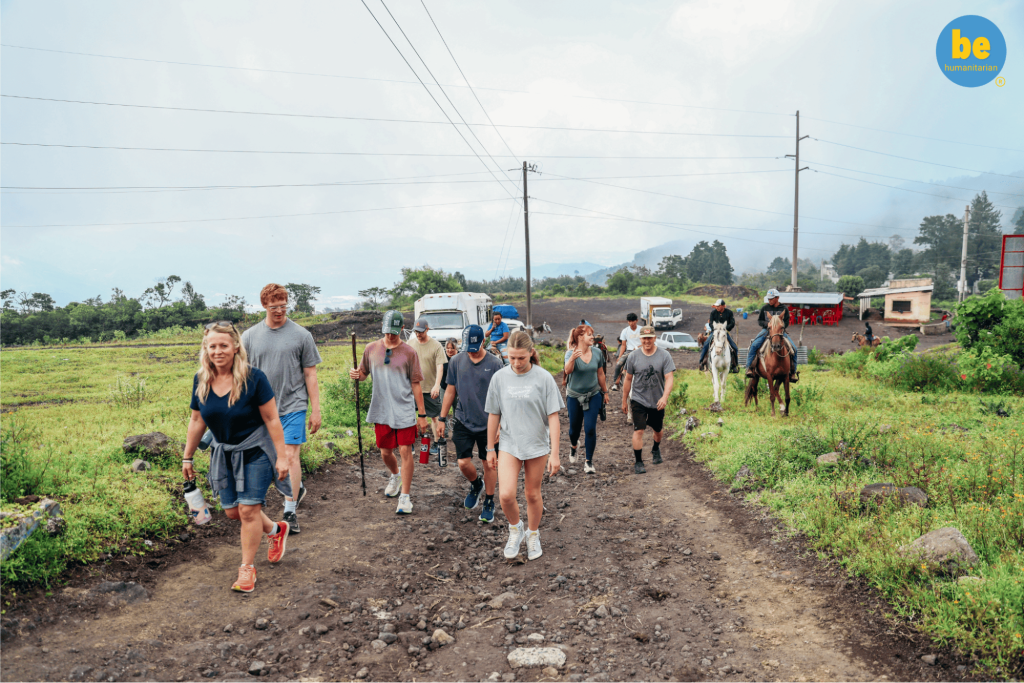 A group on what Guatemala volunteer trips suit retirees: walking a rural dirt road near a volcanic landscape
