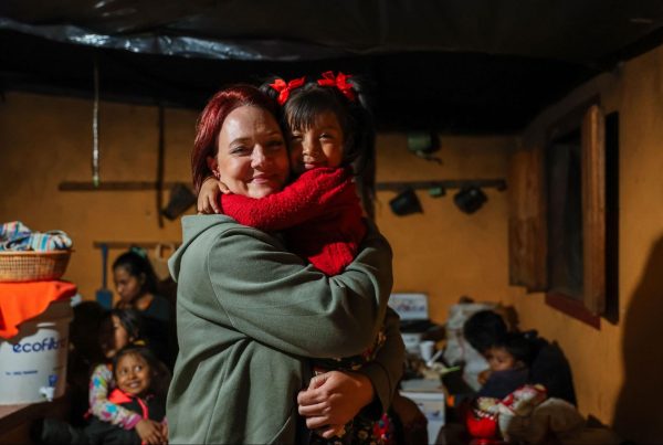 A volunteer on ethical volunteer vacations in Guatemala sharing a warm embrace with a young local girl indoors 