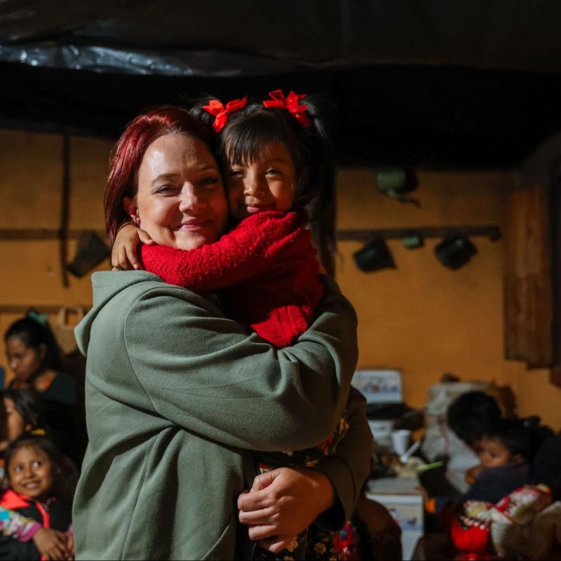 A volunteer on ethical volunteer vacations in Guatemala sharing a warm embrace with a young local girl indoors 