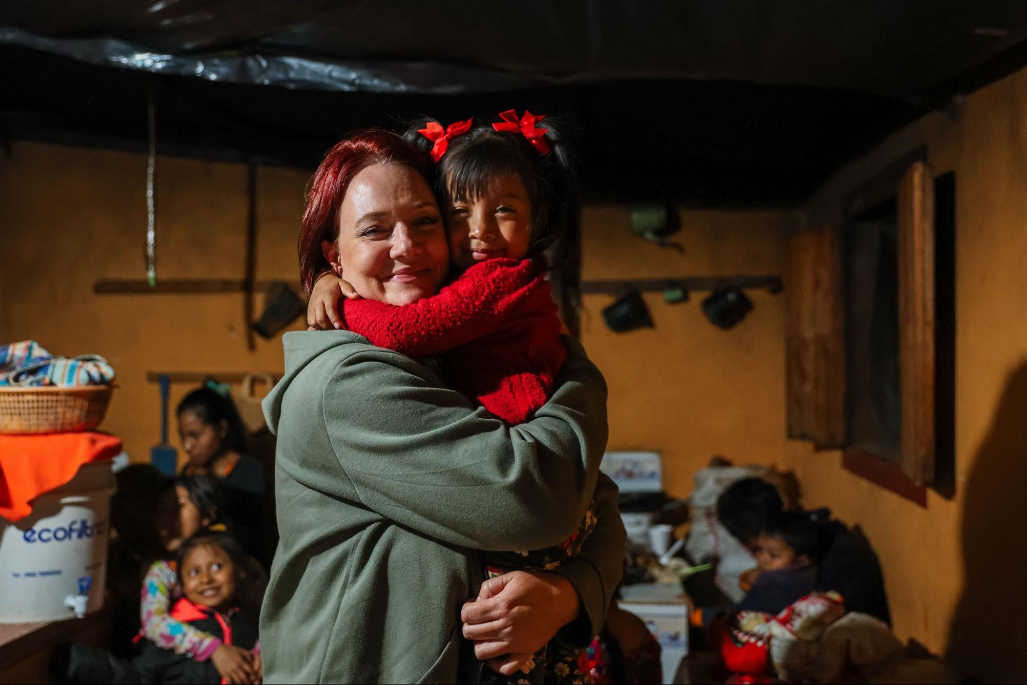 A volunteer on ethical volunteer vacations in Guatemala sharing a warm embrace with a young local girl indoors 
