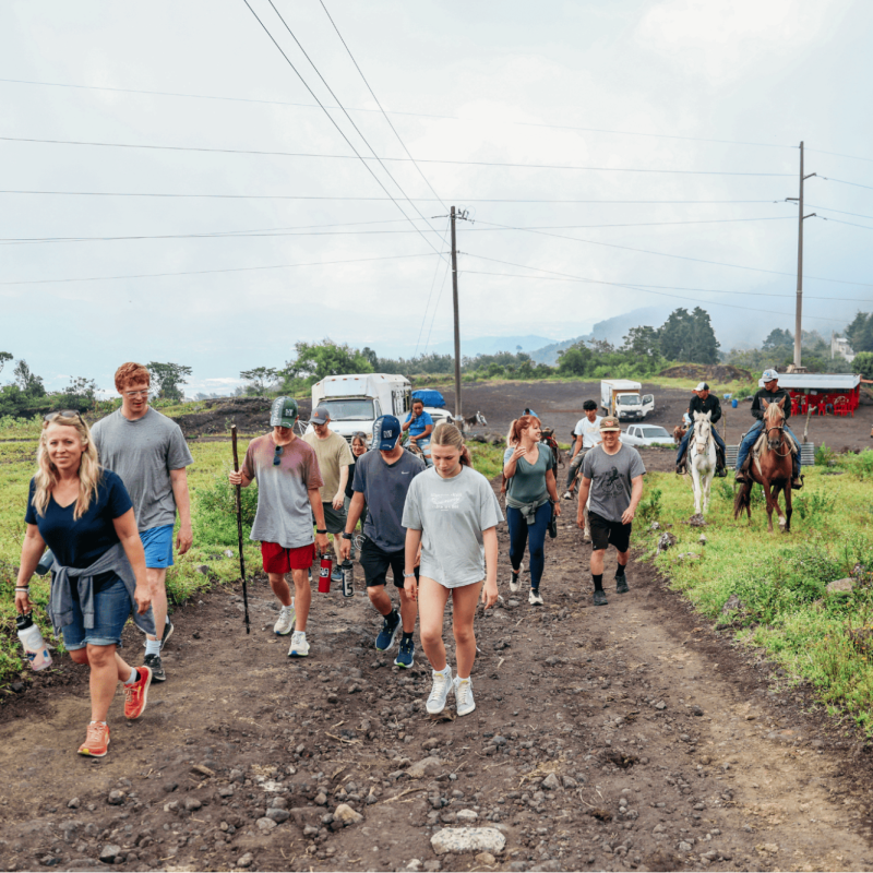 A group on what Guatemala volunteer trips suit retirees: walking a rural dirt road near a volcanic landscape