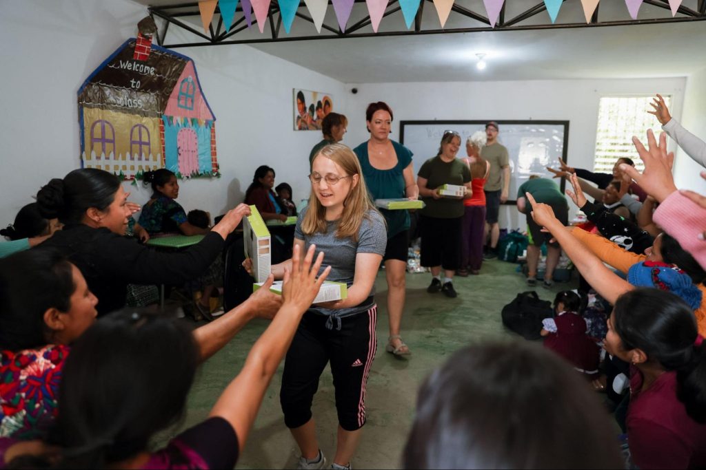 Volunteers on what Guatemala volunteer trips suit retirees, distributing supplies to local women in a classroom