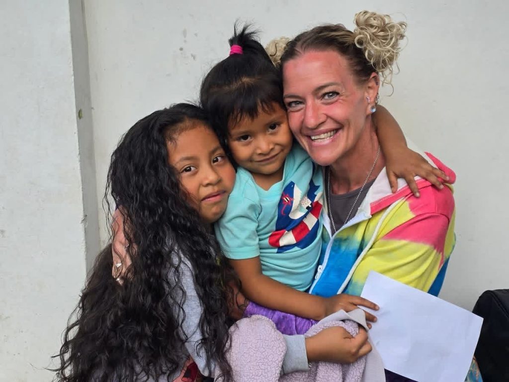Smiling woman embracing two girls, capturing what to expect sponsoring child Guatemala connections 