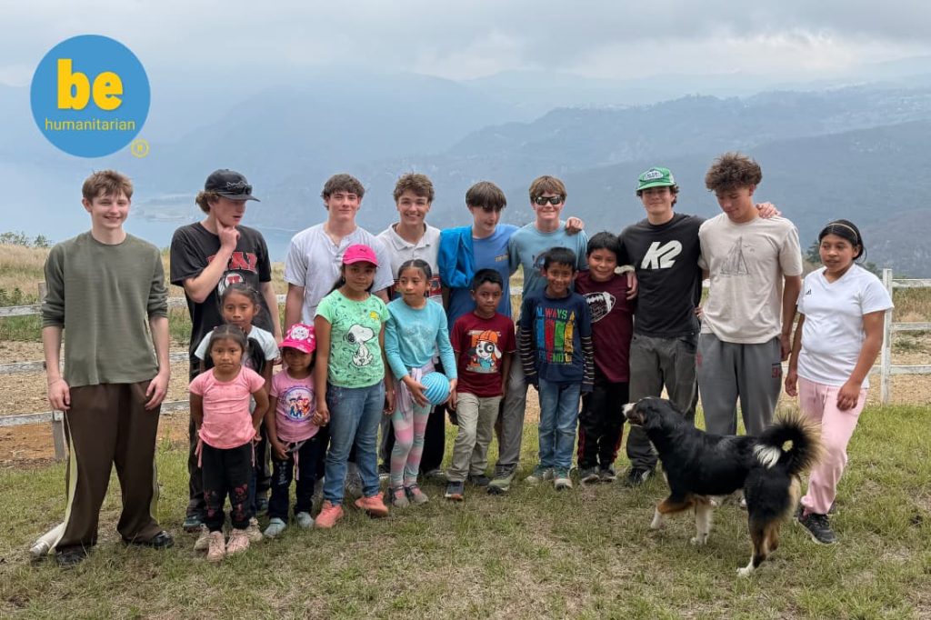 Teen volunteers posing with local children on a fight malnutrition volunteer vacation Guatemala hillside