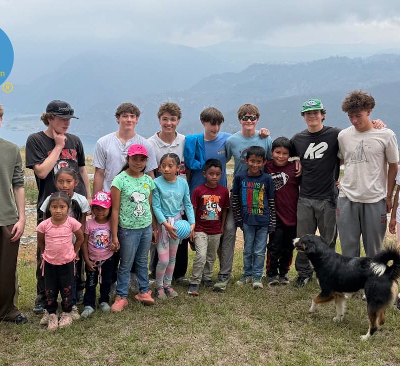 Teen volunteers posing with local children on a fight malnutrition volunteer vacation Guatemala hillside