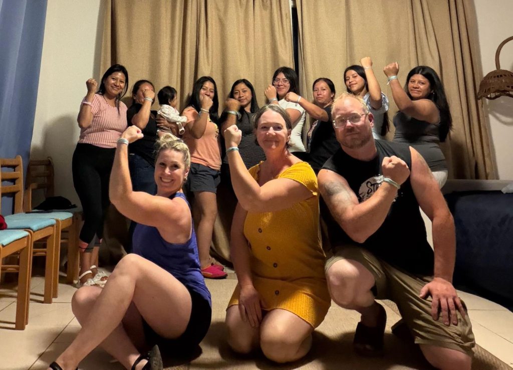 Group raises fists in unity, capturing volunteer vacation impact in Guatemala through empowerment training. 