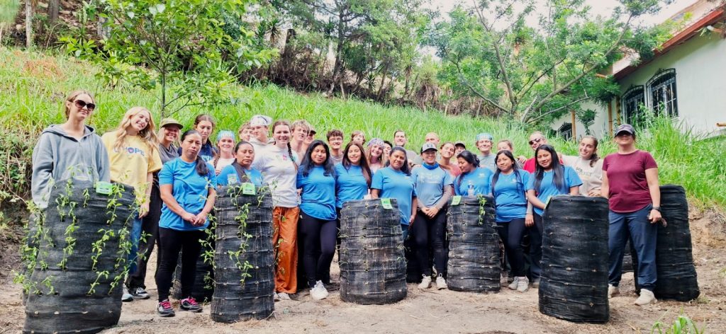 Volunteers and local women pose with plant saplings, showing what impact do Guatemala volunteers make in San Andrés. 