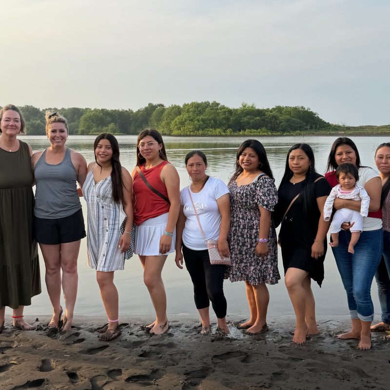 Learn how to plan a volunteer vacation Guatemala with local women by a river at sunset.