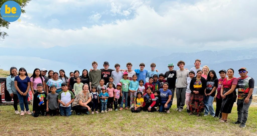 Volunteers and families pose together on a hilltop, showing the impact of child sponsorship funding in the community.